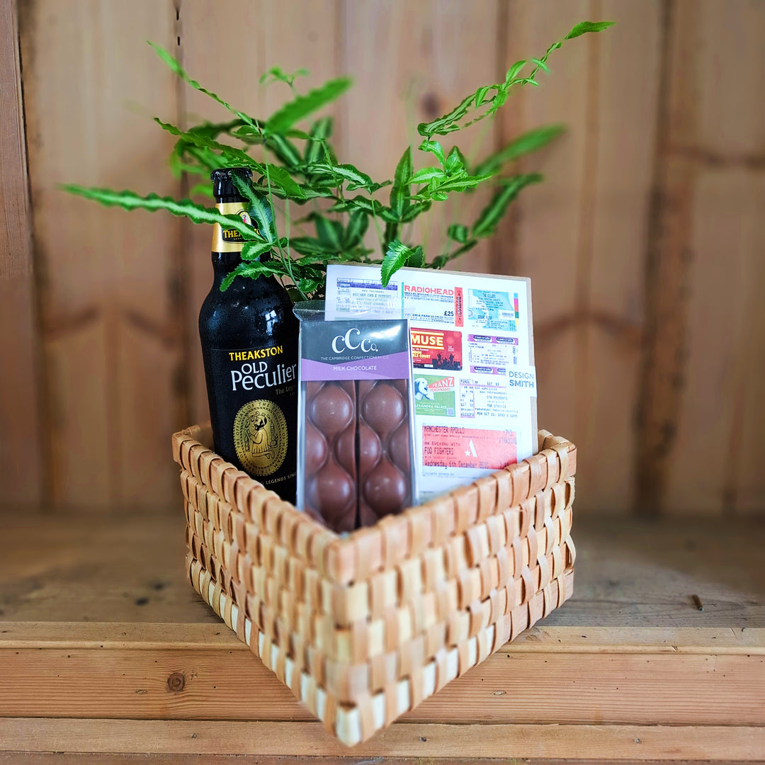 Fathers Day Plant Presentation - Magnolia the Florist Celebrate Dad with this thoughtfully curated gift basket. Presented in a gift-wrapped woven basket (21cm x 21cm x 12cm), it features a bottle of beer, a silver ribbon fern (Pteris Cretica) to brighten his space, a 100g milk chocolate bar for a sweet treat, and a Design Smith gift card for him. Perfect for Father's Day or any occasion to show appreciation. Please note: beer type and gift card design vary depending on current stock availability.  1