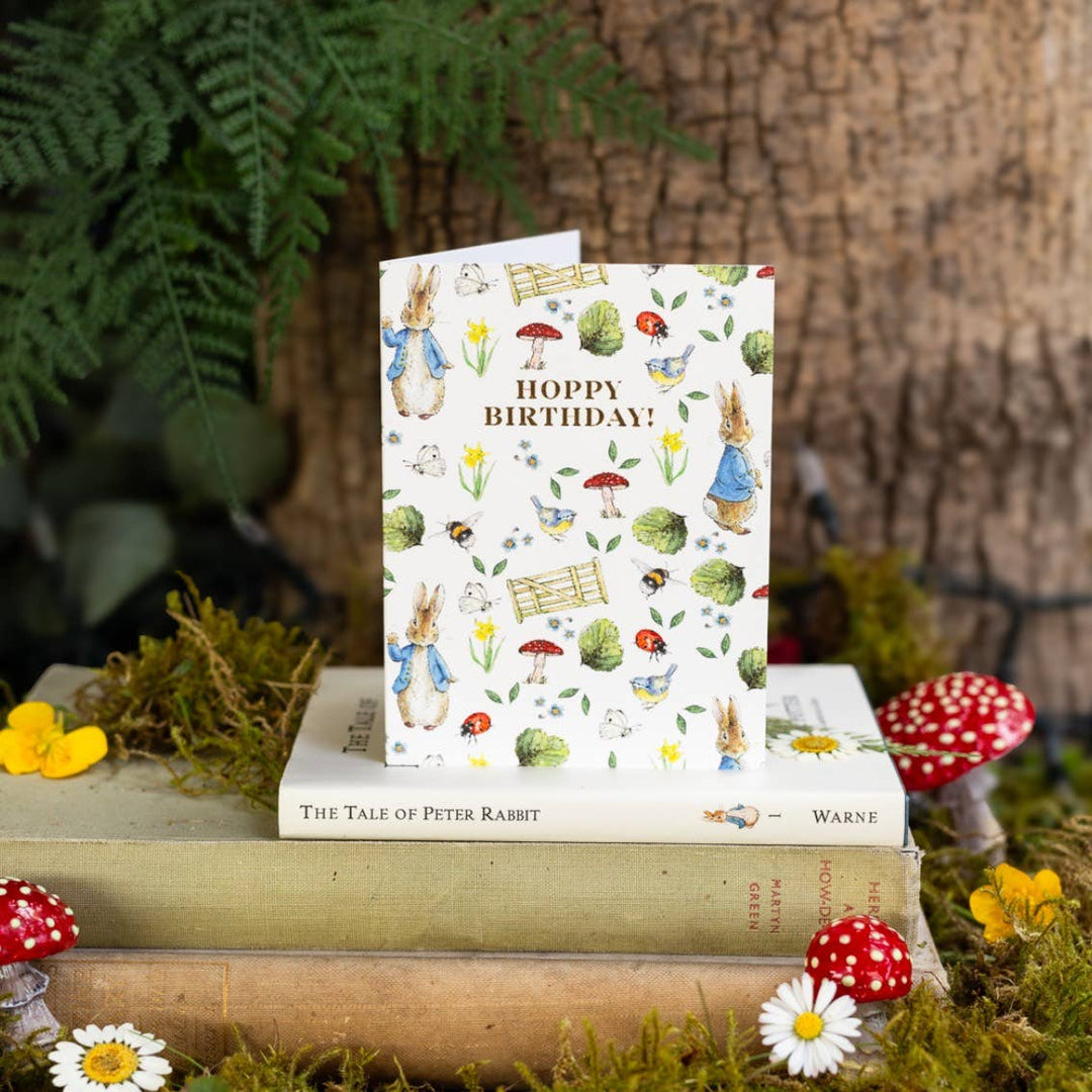 Hoppy Birthday (Peter Rabbit) Card - Magnolia the Florist Celebrate their special day with this charming Hoppy Birthday Peter Rabbit Card, featuring the beloved Beatrix Potter character. Beautifully illustrated and environmentally friendly, this cello-free card is the perfect finishing touch to a birthday gift Size is 90 × 120 mm • Blank inside • Includes white envelope  1