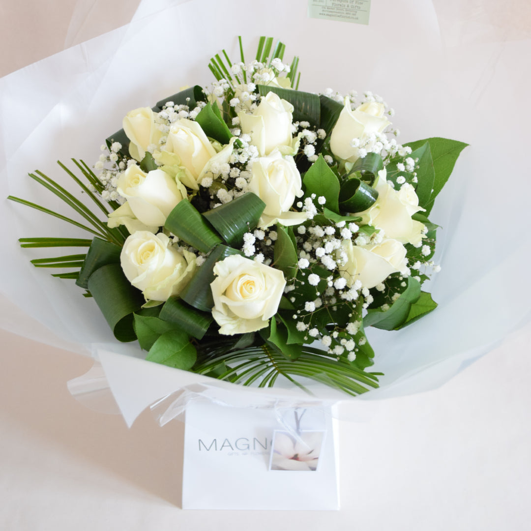 Beaumont Bouquet - Magnolia the Florist The Beaumont Bouquet from Magnolia the Florist is a celebration of luxury and refinement, masterfully hand-tied to highlight the timeless beauty of high-quality roses complemented by delicate gypsophila and lush foliage. Choose from 12, 18, 24, or 50 stems in white, red, pink, yellow, or a vibrant mixed palette. Please contact us for other colour options. Please note this item requires 1-day notice to order.  1