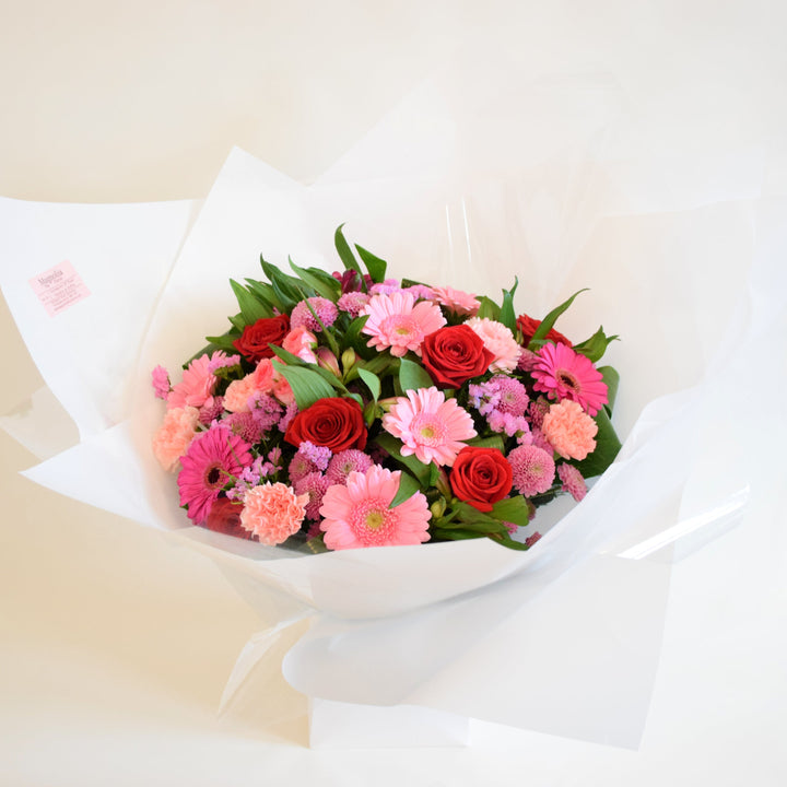 Deene Hand-Tied Bouquet - Magnolia the Florist Indulge in luxury and romance with our Deene Hand-Tied Bouquet. This exquisite bouquet features a stunning array of flowers, including Red and Pink roses, alstroemeria, carnations, and chrysanthemums and adorned with delicate greenery. Hand-tied with care and presented in one of our signature box bags, let the beauty of these blooms bring joy to your loved ones! For scale purposes, our hand-tied bags are 18cm(w) x 25cm(H).  2