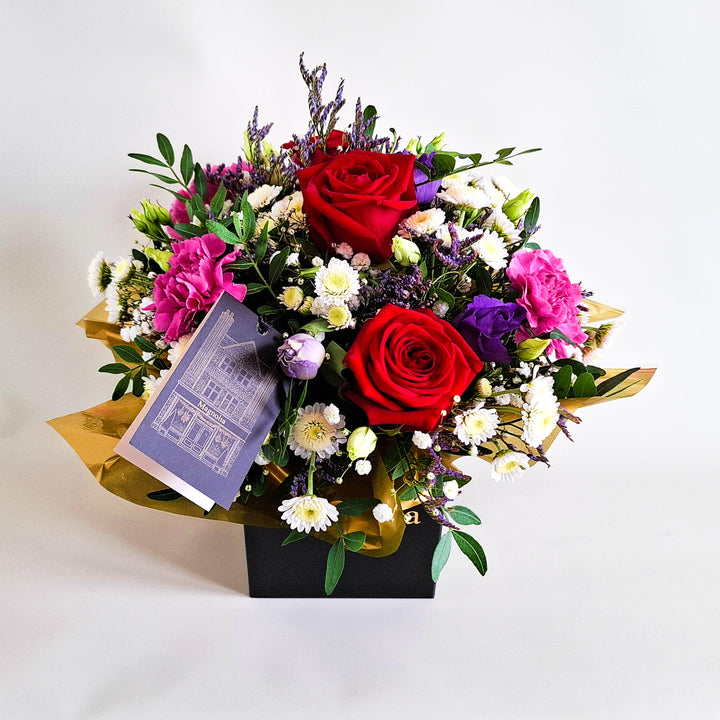 Dainty Belvedere Arrangement - Magnolia the Florist Belvedere blends rich red roses with cerise carnations, white chrysanthemum, purple lisianthus, limonium, gyp and pistache to create a romantic, luxurious floral arrangement. Presented in our Magnolia‑branded box and arranged in floral foam for long‑lasting freshness. For scale purposes, our branded box is 15cm(h) x 12cm(w) x 12cm(d), giving an overall size of approximately 25cm(h) x 18cm(w).  3