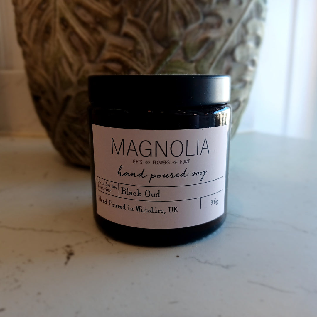 Black Oud Scented Candle - 96g - Magnolia the Florist Introduce an air of luxury with our Black Oud candle. Our scented candle exudes the warm, woody aroma of black oud. The sleek jar adds a touch of exclusivity and is perfect for setting the mood or unwinding after a long day. Enjoy the aromatic benefits while enhancing any room with a touch of elegance, made with a professional blend of scented oil & emollient wax balm.  1