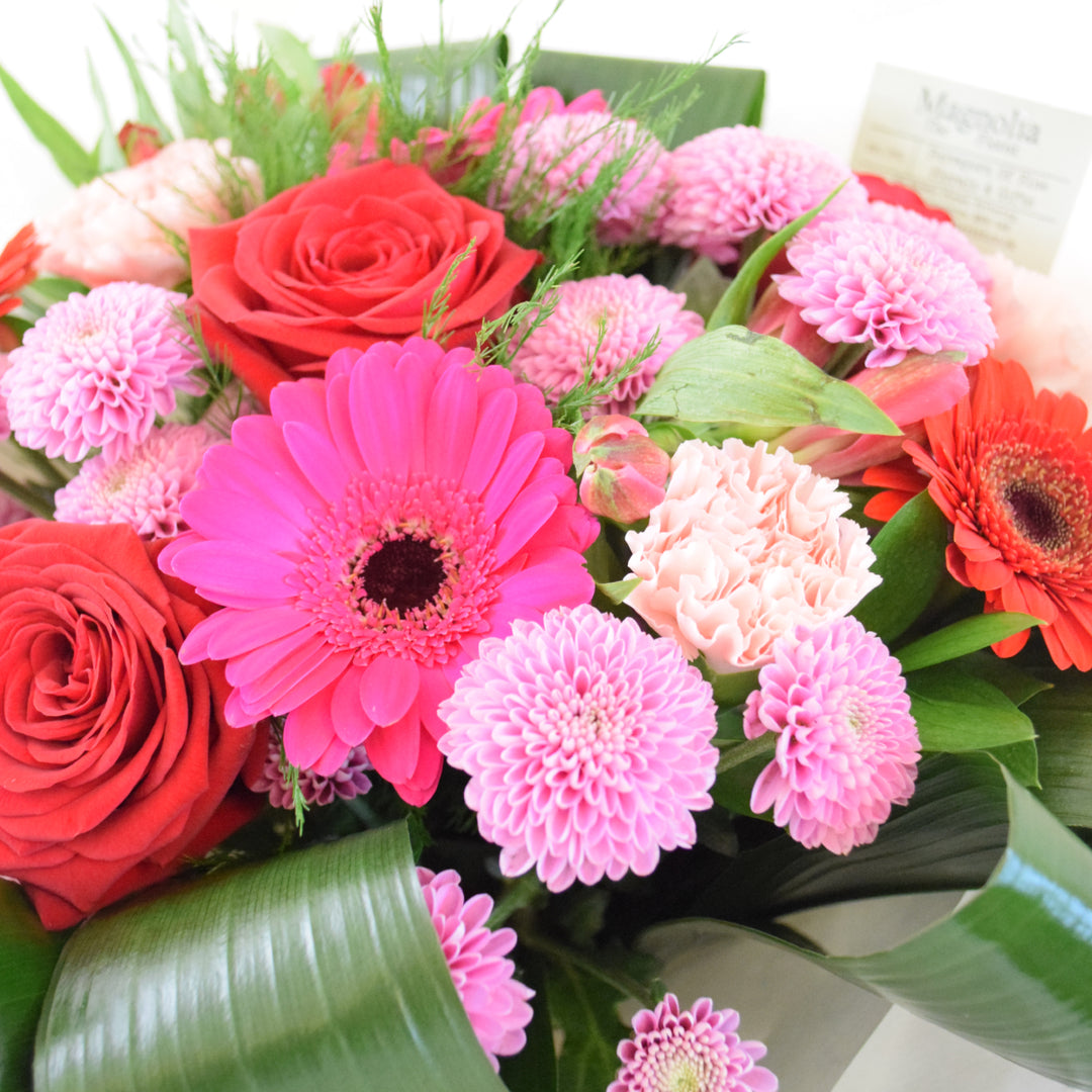 the Buckingham Bouquet from Magnolia the Florist,&amp;nbsp; features a stunning combination of red and pink-toned flowers, including roses, gerbera, alstroemeria, carnation, chrysanthemum, and foliage
