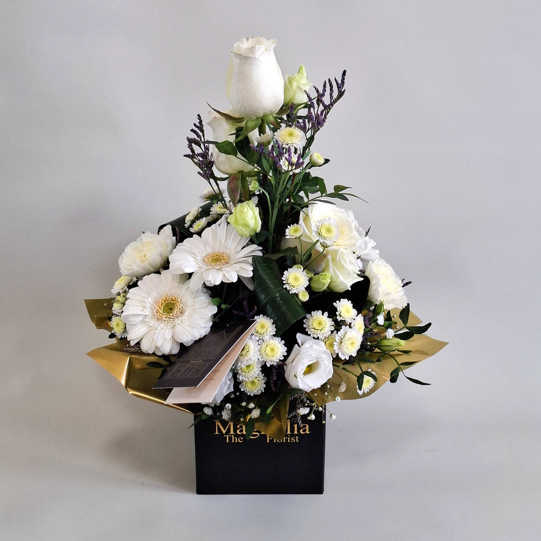Iona Arrangement - Magnolia the Florist Iona is a pure and elegant floral arrangement featuring white roses, white germini, white carnations, white chrysanthemum, white lisianthus, folded aspidistra, limonium, gyp and pistache. Presented in our Magnolia branded box and arranged in floral foam for long lasting freshness. For scale purposes, our branded box is 15cm (h) x 12cm (w) x 12cm (d), giving an overall size of approximately 35cm (h) x 18cm (w).  3