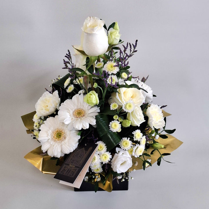 Iona Arrangement - Magnolia the Florist Iona is a pure and elegant floral arrangement featuring white roses, white germini, white carnations, white chrysanthemum, white lisianthus, folded aspidistra, limonium, gyp and pistache. Presented in our Magnolia branded box and arranged in floral foam for long lasting freshness. For scale purposes, our branded box is 15cm (h) x 12cm (w) x 12cm (d), giving an overall size of approximately 35cm (h) x 18cm (w).  2