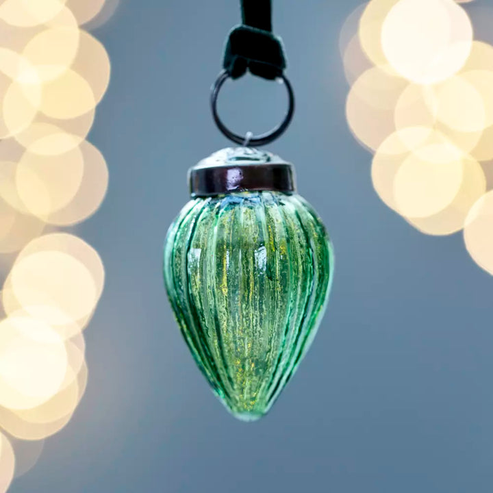 Ribbed Gourd Decoration Green With Velvet Loop 5x3cm - Magnolia the Florist Presented in an alluring clear green hue, this gourd shaped bauble looks stunning either adorning a tree or strung on a branch for a contemporary twist. With vertical ribs, light will play off the surface for amplified sparkle. The soft velvet loop in a complementary colour completes the look. Dimensions: 3 × 5 cm - Glass  2