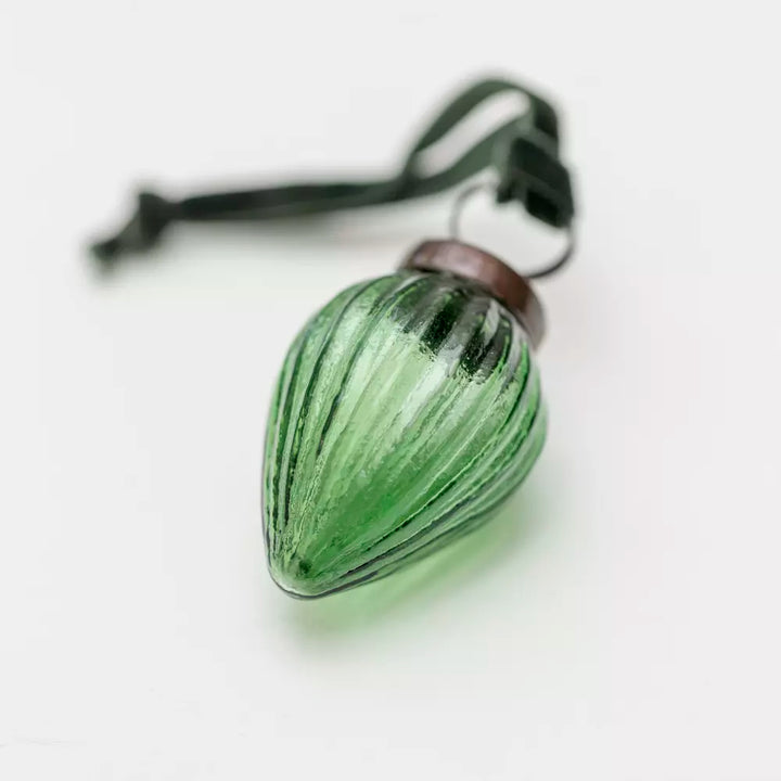 Ribbed Gourd Decoration Green With Velvet Loop 5x3cm - Magnolia the Florist Presented in an alluring clear green hue, this gourd shaped bauble looks stunning either adorning a tree or strung on a branch for a contemporary twist. With vertical ribs, light will play off the surface for amplified sparkle. The soft velvet loop in a complementary colour completes the look. Dimensions: 3 × 5 cm - Glass  3