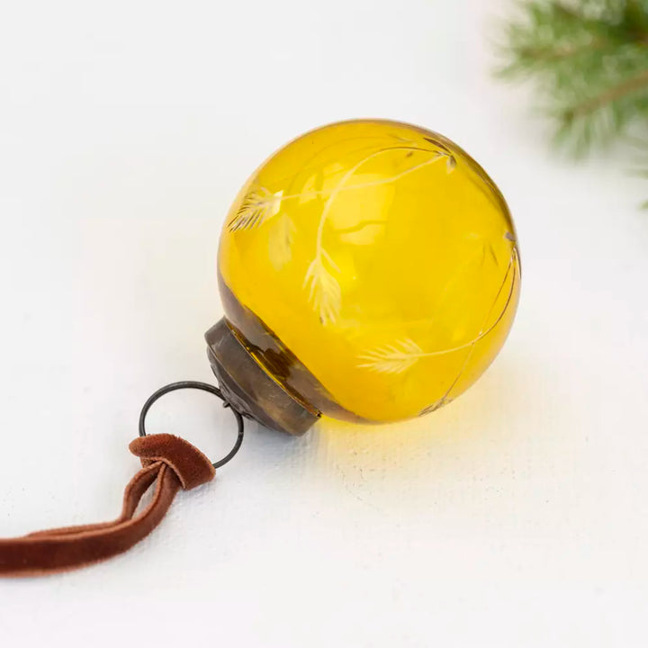 Etched Round Decoration  - Yellow - 5cm - Magnolia the Florist Add a touch of sophistication to your Christmas tree with this exquisite round hanging decoration. Crafted from glass in a charming yellow hue, this bauble features an elegant etched pattern that catches the light beautifully. Measuring 5cm in diameter, it is the perfect size for adding subtle elegance to your festive display. This beautiful bauble is sure to bring warmth and a playful style to your celebrations. Dimensions: 5 cm - Glass  2