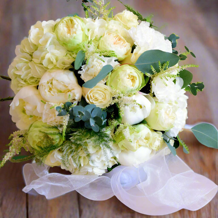 Bridal Bouquet Knot - Magnolia the Florist The roses take centre-stage in this Bridal bouquet, with the stems cut short in compact, round designs for an effortlessly stylish, deeply romantic look. Please note this item requires a minimum 1-day notice to order.  1