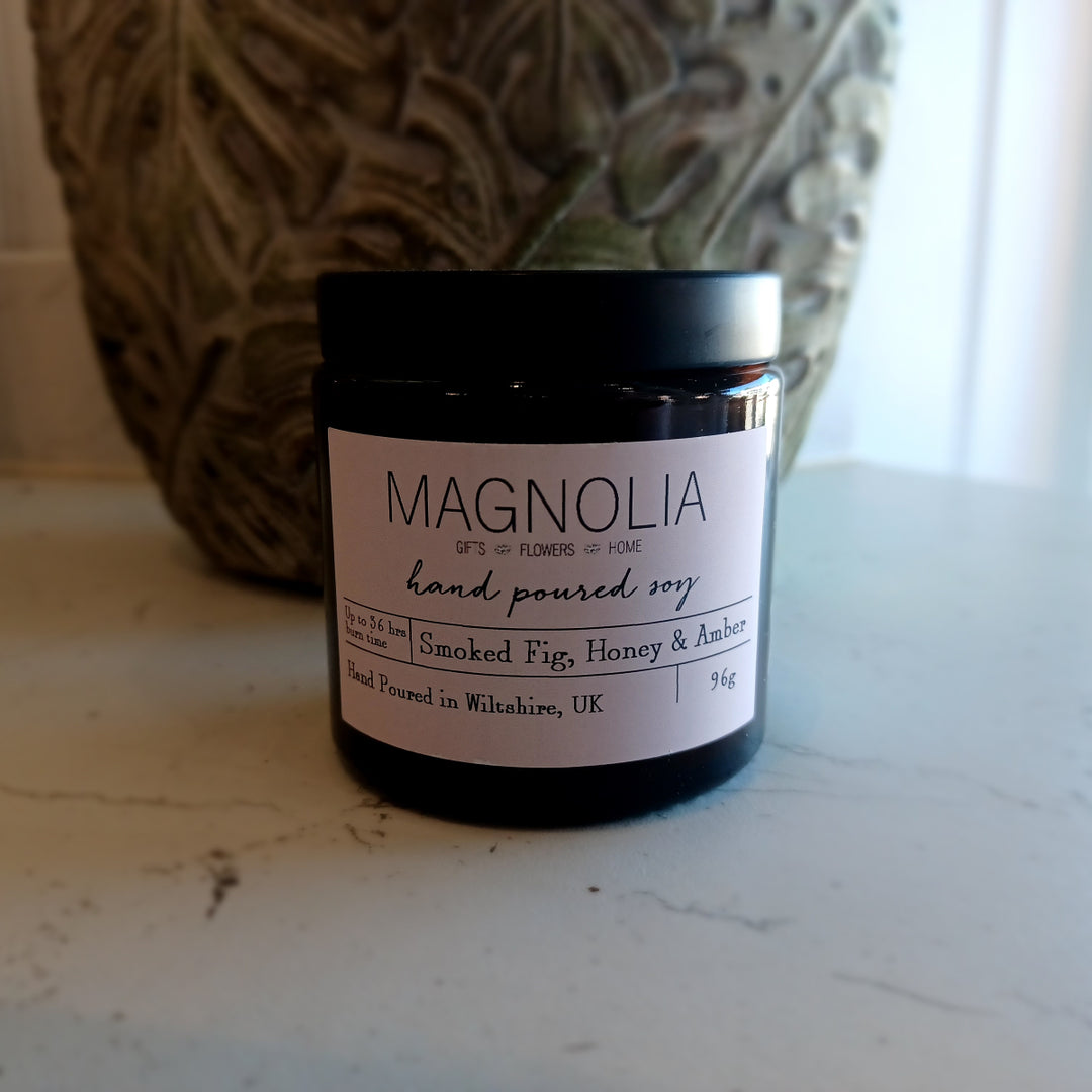 Smoked Fig, Honey & Amber Scented Candle - 96g - Magnolia the Florist Indulge in luxury with our exclusive smoked fig, honey, and amber-scented candle. Hand-poured into our signature screw-top jar, this candle will immerse your senses in sensual notes of smoky fig, sweet honey, and warm amber. Elevate any space with this exquisite and sophisticated fragrance. IEnjoy the aromatic benefits while enhancing any room with a touch of elegance, made with a professional blend of scented oil & emollient wax balm.  1