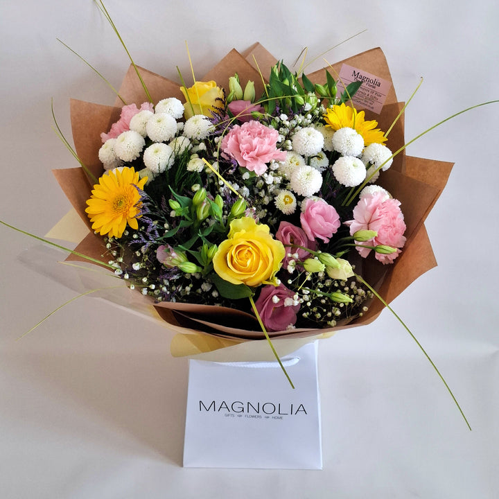 Lilford Bouquet - Magnolia the Florist The Lilford Bouquet is an expertly crafted hand-tied arrangement showcasing a refined blend of Germini, Roses, Alstroemeria, Eustoma, Carnation, Gyp, Chrysanthemums, and Statice in harmonious shades of pink, yellow, and white. Finished with lush greenery, this bouquet balances texture and colour to create a sophisticated, elegant statement suitable for any occasion.  1