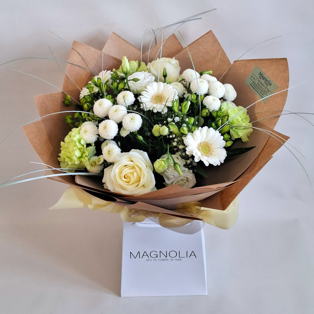 Sibbertoft Bouquet - Magnolia the Florist The Sibbertoft Bouquet showcases a sophisticated hand-tied arrangement of fresh Germini, Carnations, Eustoma, Roses, Alstroemeria, Chrysanthemums, and Gypsophila, elegantly presented in white and green tones. Enhanced with lush greenery, this bouquet offers a fresh, timeless appeal suited for both formal and intimate settings.  1