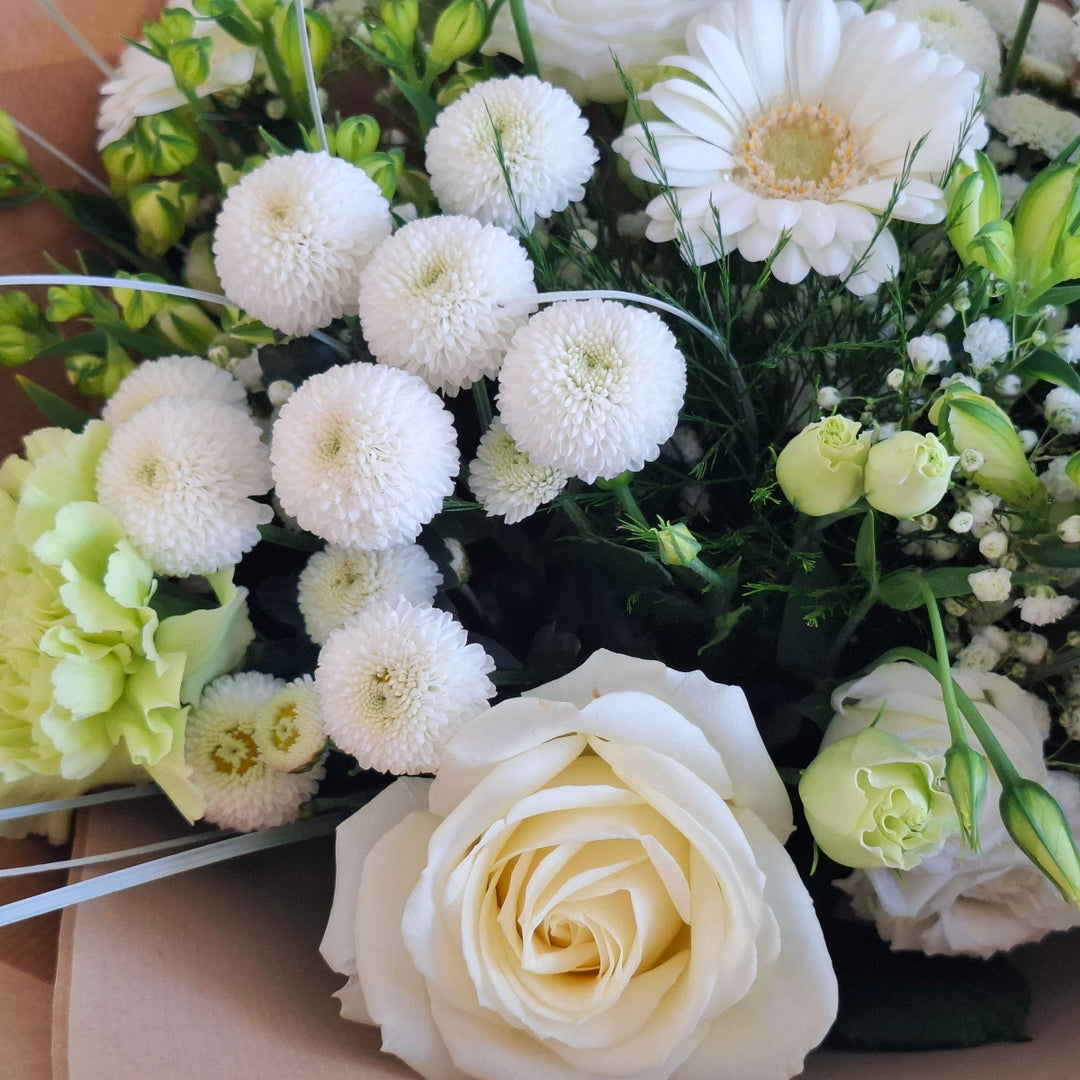 Sibbertoft Bouquet - Magnolia the Florist The Sibbertoft Bouquet showcases a sophisticated hand-tied arrangement of fresh Germini, Carnations, Eustoma, Roses, Alstroemeria, Chrysanthemums, and Gypsophila, elegantly presented in white and green tones. Enhanced with lush greenery, this bouquet offers a fresh, timeless appeal suited for both formal and intimate settings.  3