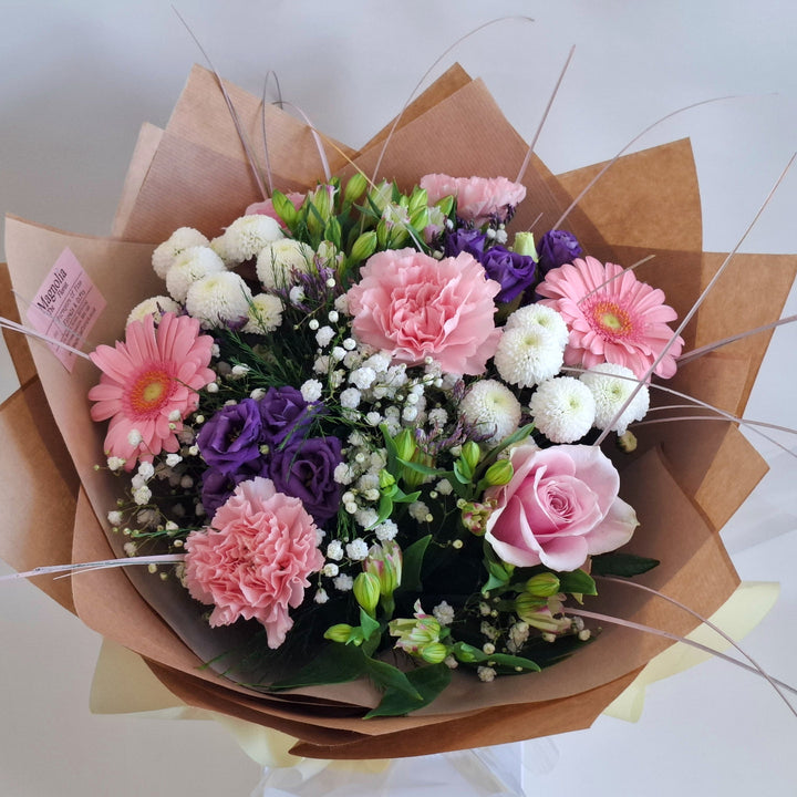 Warkton Bouquet - Magnolia the Florist The Warkton Bouquet is an expertly crafted, hand-tied arrangement that blends Germini, Eustoma, Alstroemeria, Roses, Gypsophila, Chrysanthemums, and Statice in harmonious shades of pink, white, and purple. Accented with fresh greenery, this bouquet offers a refined balance of texture and colour, perfect for conveying elegance and thoughtful sentiment on any occasion.  2