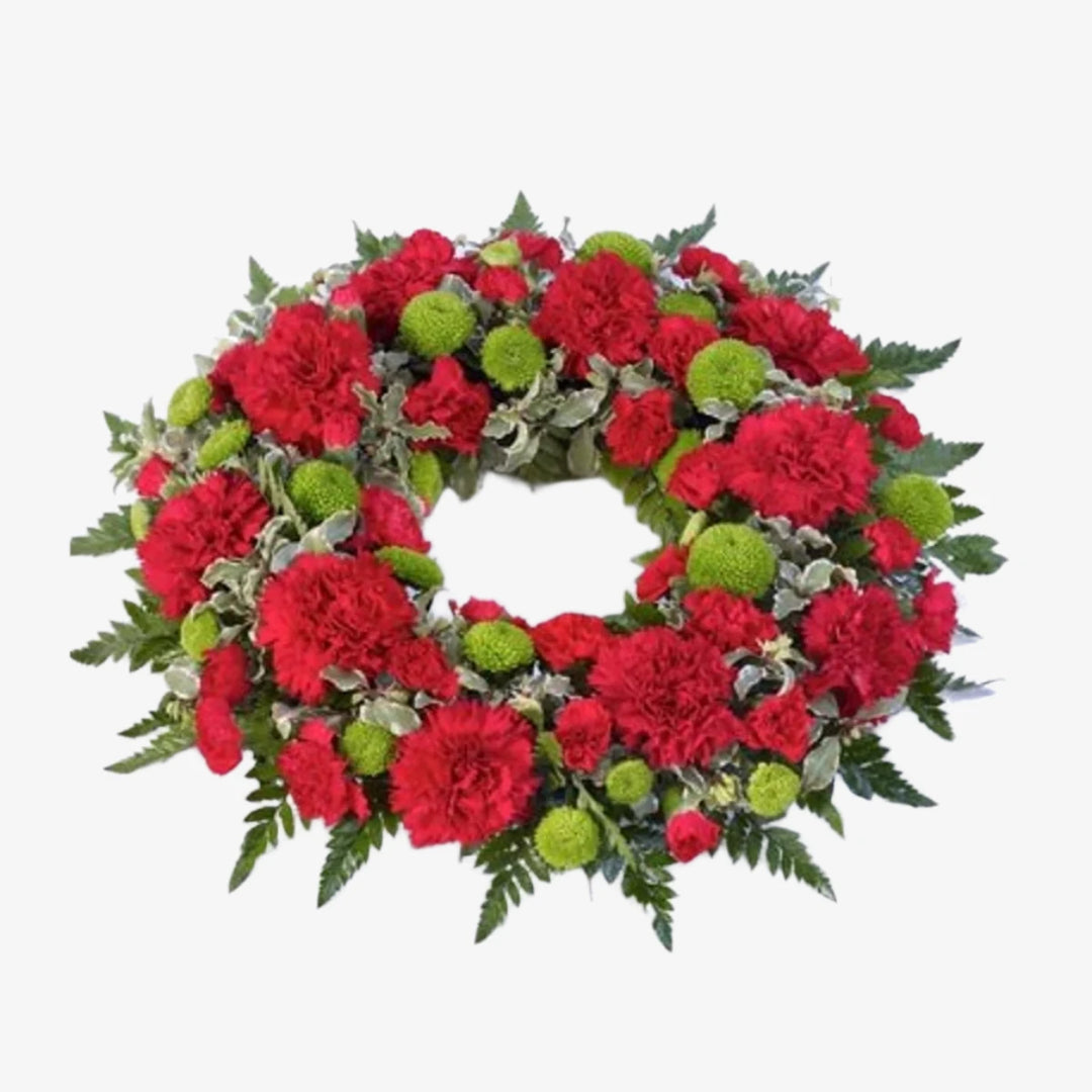 Carnation Wreath - Magnolia the Florist This elegant funeral wreath blends bloom and spray carnations, accented by green button chrysanthemums and foliage. The image depicts the beautiful contrast of red carnations against a bed of greenery and we can change the carnation colour if required, please select from below. If you cannot find what you want on our site, please call our sales team, we're always happy to assist you. This item requires 2 days notice to order.  1
